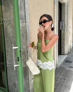 Model wearing green satin camisole and pants set with white lace trim detail outdoors