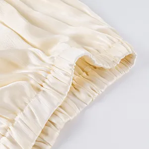 Detailopname van de elastische tailleband en geplooide satijntextuur van de broek