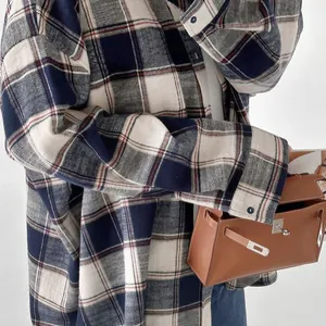 Detailweergave van een oversized flanellen ruitjeshemd met blauw en wit ruitpatroon.