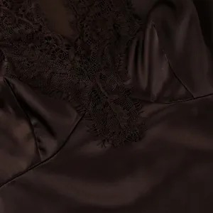 Detailed macro view of the intricate lace trim and glossy brown satin fabric of the top