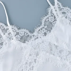 Close-up detail of delicate white floral lace patchwork on a stylish satin camisole top.