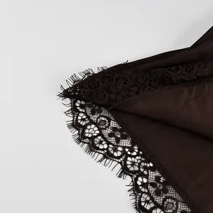 Close-up of delicate black eyelash lace trim on a dark brown satin camisole top