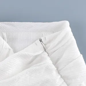 Detail van de onzichtbare rits op witte geplisseerde lantaarnbroek voor dames, close-up.