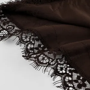 Detailed macro view showing the intricate lace trim on dark brown satin fabric hemline