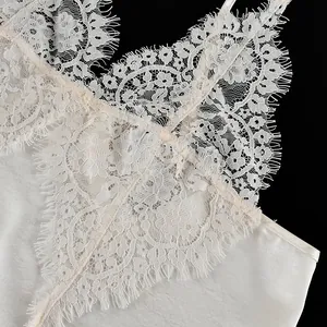 Detail of white V-neck lace camisole showing delicate eyelash trim and silky fabric.