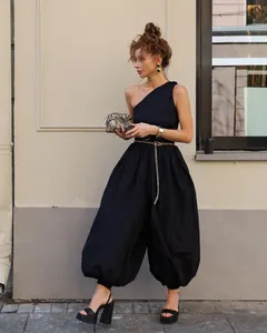 Stylish woman in black one-shoulder balloon pants jumpsuit for chic street fashion style.