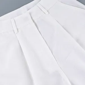 Detailed view of the waistband and belt loops on white high-waisted wide-leg trousers