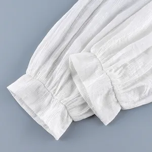 Detailopname van de geplooide boorden van een witte plissélantaarnbroek, stoftextuur.