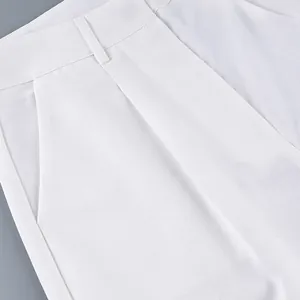 Detail view of high-waisted white wide-leg trousers showing waist and pocket texture