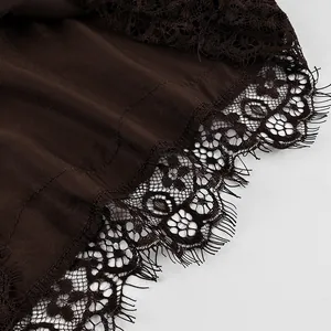 Close-up detail of delicate black eyelash lace trim on a dark brown satin fabric