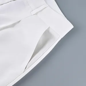 Detail of high-waist white wide-leg trousers showing pocket and stitching.