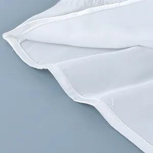 Detail view of the fine lace trim and clean hemline on this white camisole top.