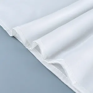 Macro detail of white satin fabric showing high-quality hem stitching on a stylish top.