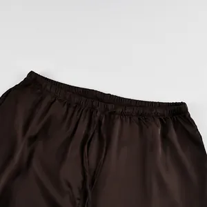 Close-up detail of the elastic waistband and drawstring on dark brown satin long pants