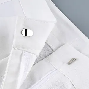 Detailed view of metal hook and bar closure on white high-waisted wide-leg trousers