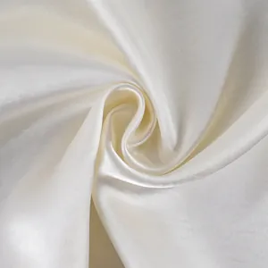 Macro view of elegant cream white satin fabric showing smooth and glossy silk texture.
