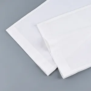 Detail view of the wide-leg hem of white high-waisted trousers with precise stitching