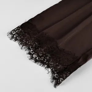 Intricate eyelash lace trim detail on the hem of elegant dark brown satin trousers