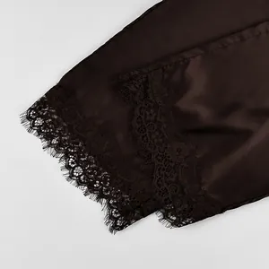 Macro view of delicate black lace trim on dark brown satin pajama pants hem line