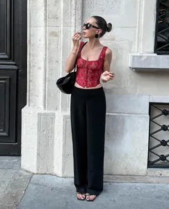 Detailed view of a fashionable red lace corset top styled with black wide-leg pants.