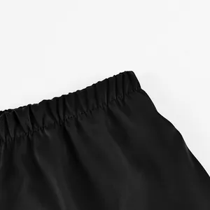 Close-up view showing the elastic waistband detail of black faux acetate satin trousers