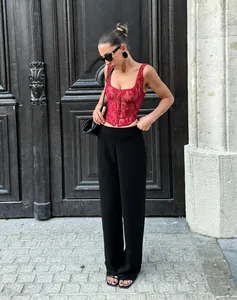 Detailed street style view of a sexy red lace corset top paired with black trousers.