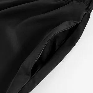 Close-up view of the side pocket detail on black acetate satin straight-leg trousers.