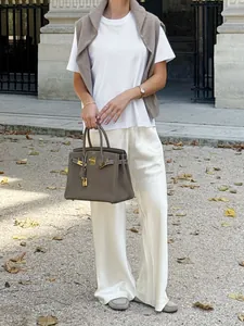 Close-up of elegant cream satin trousers showing the fluid drape and premium fit.