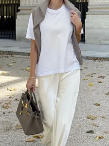 Detail view of white satin high-waisted trousers with elegant drape and smooth texture