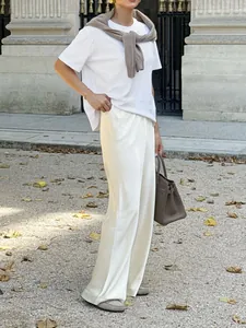 Close-up detail of white acetate-like satin wide-leg pants showing elegant drape.