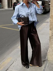 Close-up of brown satin high-waisted wide-leg pants featuring elegant drape and texture