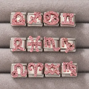 Vista dettagliata dei dodici charm zodiaco con strass rosa su velluto grigio scuro