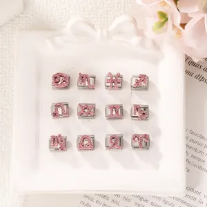 Primo piano di charm zodiacali in strass rosa per bracciali modulari fai-da-te su vassoio bianco