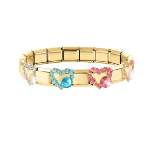 Gros plan d'un bracelet modulaire en acier inoxydable doré avec des breloques cœur.