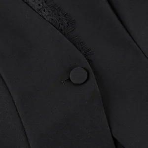 Detail van zwarte kanten bies en met stof beklede knoop op elegant jasje