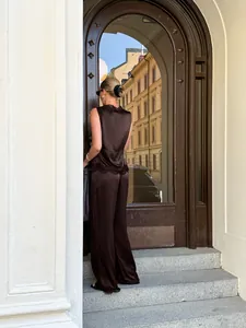 Back view of a woman wearing a chocolate brown satin lace-trim tank and wide-leg trousers set