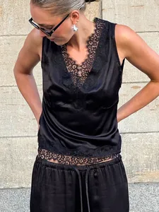 Close-up detail of a black satin V-neck camisole featuring delicate lace trim on model