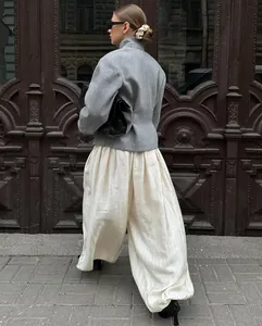 Street style detail of loose cream lantern pants paired with a gray jacket and heels.