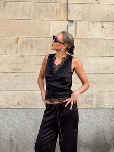 Stylish street style shot of black satin camisole with lace trim and matching trousers