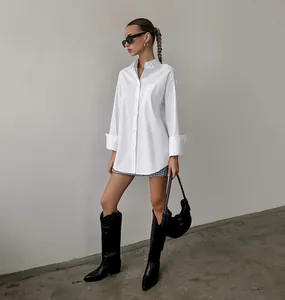 Detail of an oversized white boyfriend-style shirt styled with black boots and bag.