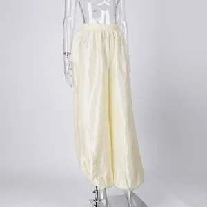 Macro detail view of cream-colored lantern pants with elegant shimmering crinkle texture