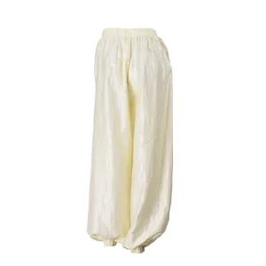 Close-up detail of shiny, textured cream-white fabric and elastic waist on these harem pants.