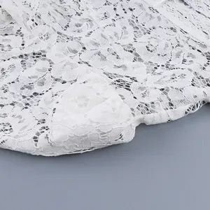 Primo piano dettagliato che mostra delicati ricami in pizzo bianco su camicetta chic.