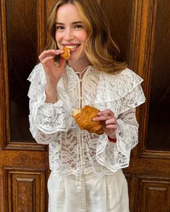 Detail van witte kant doorschijnende blouse met dubbele ruffelkraag en bloemmotief