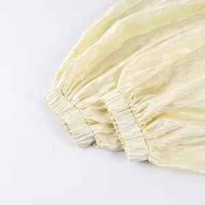 Close-up of elastic cuffs on champagne lantern pants with shiny textured fabric
