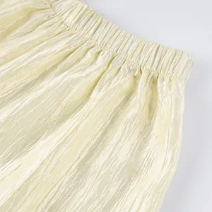 Detailed macro view of the pleated texture and elastic waistband on light yellow lantern pants