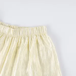 Close-up of shimmery crinkled fabric and elastic waistband on cream lantern pants