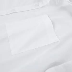 Detailed view of the breast pocket and buttons on oversized white shirt for women