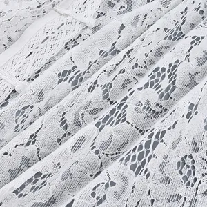 Primo piano del delicato ricamo in pizzo floreale bianco su una camicetta estiva di moda
