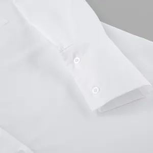 Macro view showing the buttoned cuff detail of a minimalist white oversized shirt